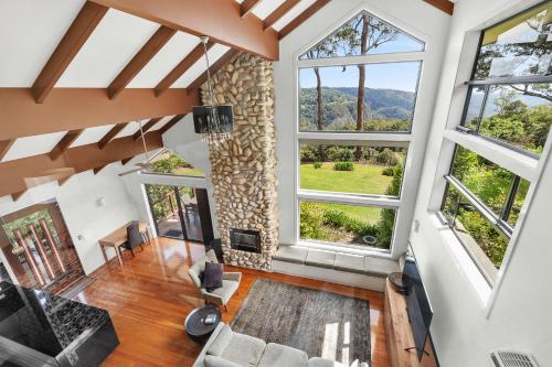 an open living room with large windows and a stone wall at Edges by St Bernards Hotel in Mount Tamborine
