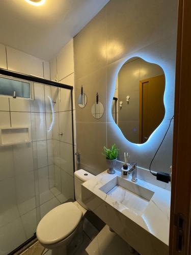 a bathroom with a toilet and a sink and a mirror at Flor Da Amazônia 2, Vista para o Bosque in Ananindeua