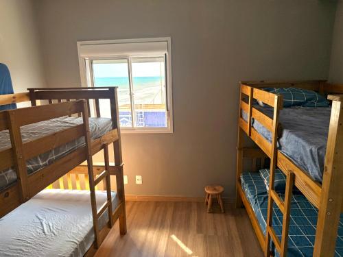 a room with three bunk beds and a window at Piscina Lazer Frente ao Mar in Mongaguá