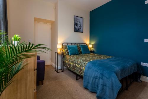 a bedroom with a bed and a blue wall at Two Bed Apartment RYTON With Free Parking in Ryton