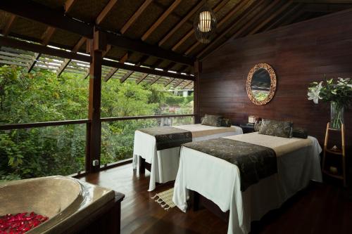 a room with two beds and a large window at Sanctoo Suites & Villas in Gianyar