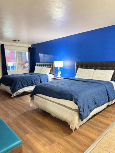 two beds in a bedroom with a blue wall at B&J HOTEL AND APARTMENTS in Pecos
