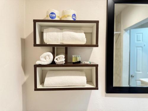 a bathroom with two shelves with towels and a mirror at B&J HOTEL AND APARTMENTS in Pecos