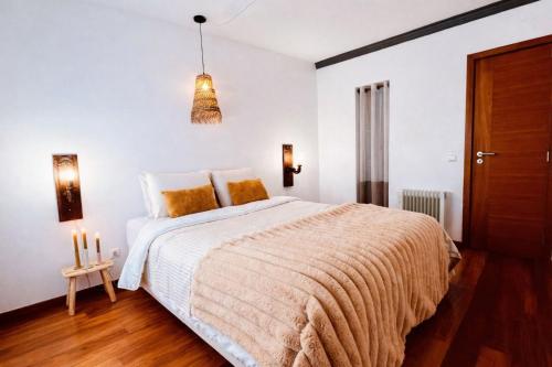 a white bedroom with a large bed and a chandelier at Villa Pinheirinhos - Enjoy the Nature & Wild Beaches of Sesimbra! in Sesimbra