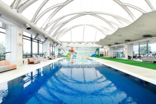 a large swimming pool with a large glass ceiling at 9stayリゾートテクノポート福井 in Sakai