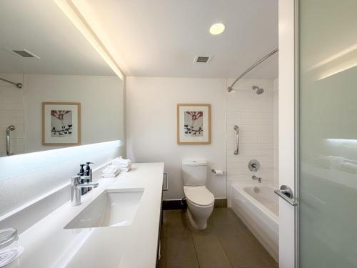 a white bathroom with a toilet and a sink at Coast Bastion Hotel in Nanaimo