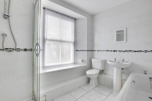 a white bathroom with a toilet and a tub and a sink at 2 Bed in Mousehole oc-mizpah in Mousehole