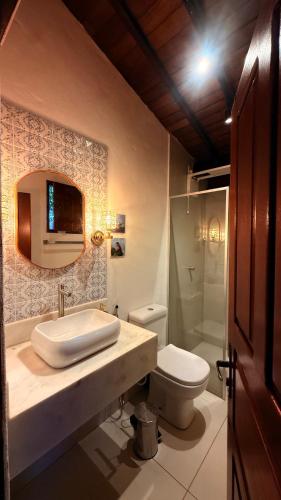 a bathroom with a sink and a toilet and a mirror at Casa Sol Piscina e Cachoeira in Pirenópolis
