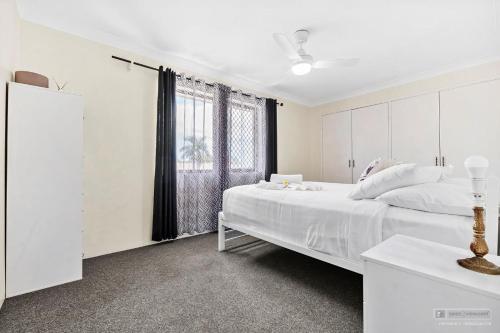 a white bedroom with a large bed and a window at Crystal Waters-2 bed, 2 bathroom, Beachfront Unit! in Bongaree