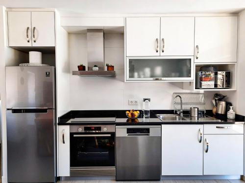 a kitchen with white cabinets and a stainless steel refrigerator at Casa do Abade - Country House in Viseu
