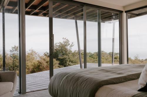 a bedroom with a bed and large glass windows at Peak View Retreat in Nelson