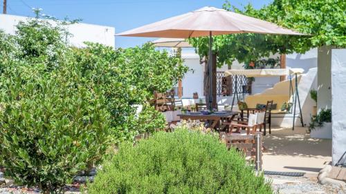 a patio with an umbrella and tables and chairs at Casa de Flores 1 in Plaka Milou