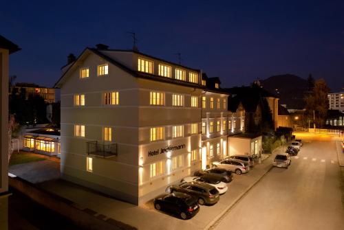 a building with cars parked in a parking lot at Das Jedermann Boutiquehotel mit Stadtgarten in Salzburg