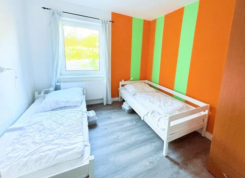 two beds in a room with orange and green stripes at Haus Waldblick - Natur pur am Rande des Nationalparks Jasmund in Sassnitz