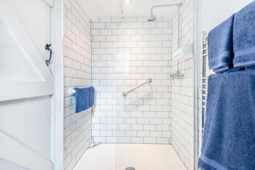 a white bathroom with a shower with blue towels at 1 Bed in Swanage oc-l30493 in Langton Matravers