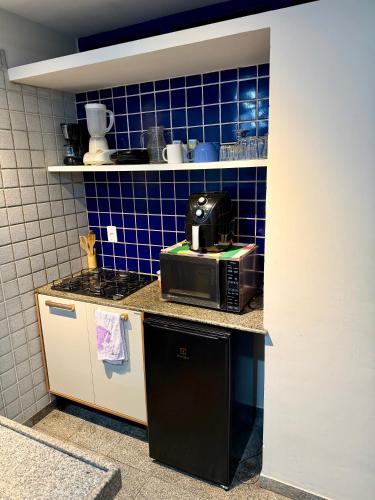 a small kitchen with a microwave and blue tiles at Flat em natal beira mar in Natal