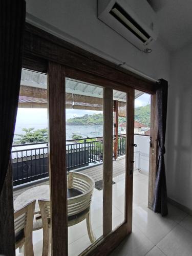 a room with a view of the ocean from a balcony at Dharma Yoga Homestay dan hostel in Amed