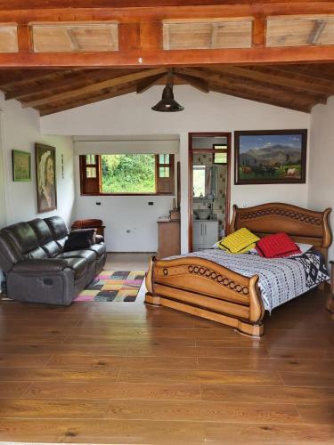 a bedroom with a large bed and a couch at Kumanday Lodge in Pereira