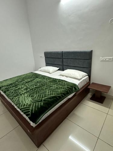 a bed with a green blanket and a wooden table at Royal living hotal in Bathinda