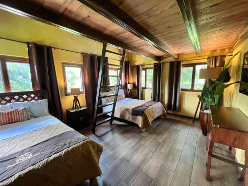 a bedroom with two beds and a desk and windows at Hermosa cabaña con terraza para disfrutar Cabañas puerta del bosque Mazamitla in Mazamitla