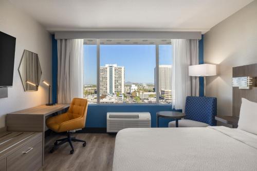 a hotel room with a bed and a desk and a window at Holiday Inn Express & Suites Phoenix - Midtown, an IHG Hotel in Phoenix