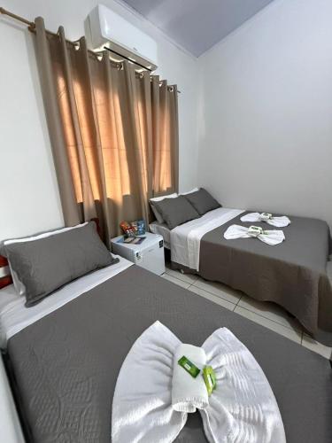 a bedroom with two beds and a window with curtains at Pousada Nova Estrela da Canastra in Delfinópolis