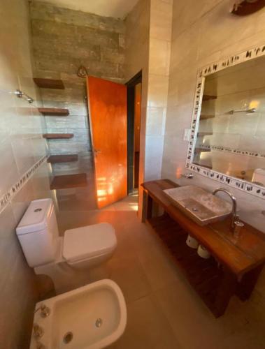 a bathroom with a toilet and a sink and a mirror at Casona de Montaña in Los Hornillos