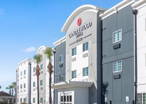 an apartment building with palm trees in front of it at Candlewood Suites Avondale-New Orleans by IHG in Avondale
