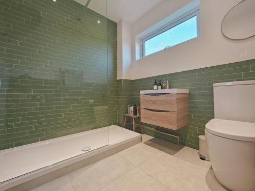 a bathroom with a tub and a toilet and green tiles at 5 Bed in Tealby oc-t30618 in Tealby