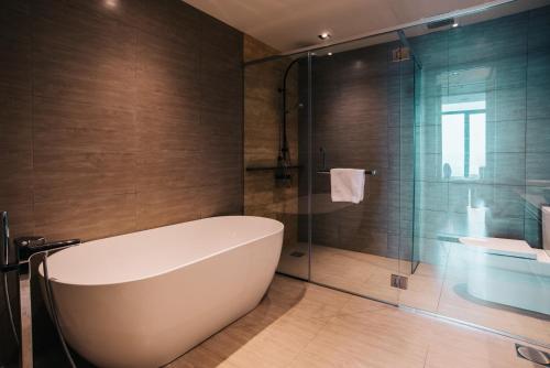 a bathroom with a tub and a glass shower at ExpressionZ Suites KLCC in Kuala Lumpur