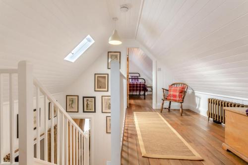 a hallway with white walls and a staircase with a red chair at 2 Bed in Ardgay oc-w30780 in Achnahanat