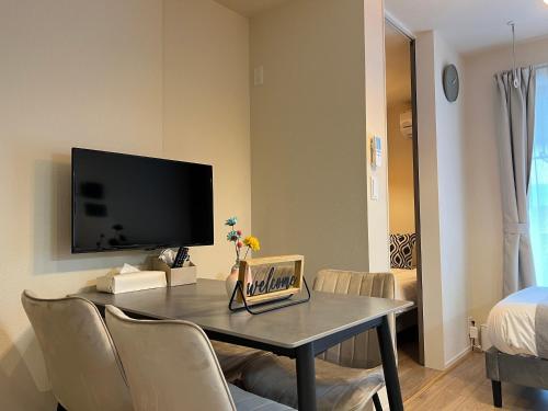 a living room with a table with chairs and a tv at nestay apartment tokyo sumida in Tokyo
