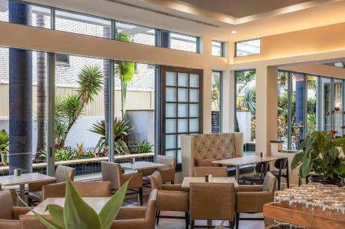 a restaurant with tables and chairs and large windows at Mantra Legends Hotel in Gold Coast