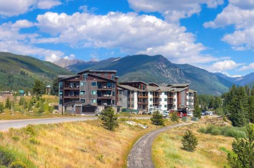an apartment building on a hill with mountains in the background at Lakeside Village by Vail Resorts in Keystone