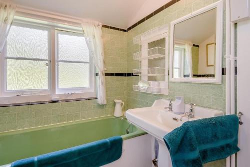a bathroom with a sink and a tub and a mirror at 2 Bed in Stalham oc-u32571 in Stalham