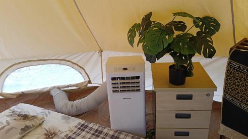 a room with a plant and an air conditioner in a tent at Gaharu glamping park in Jerantut