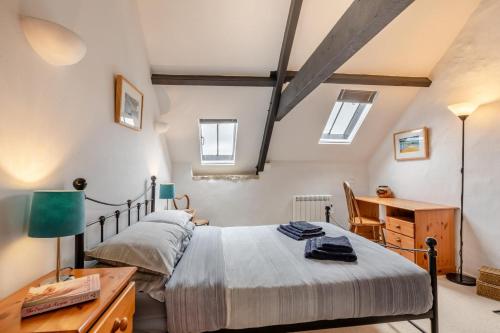 a bedroom with a bed and a desk and windows at 2 Bed in Chideock oc-g32451 in Chideock