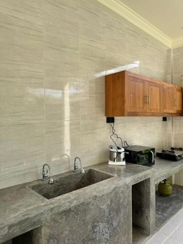a kitchen with a large sink and wooden cabinets at Teba junjungan cottages & villa in Ubud