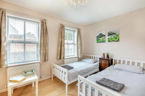 two beds in a bedroom with two windows at 2 Bed in Aspatria oc-p32645 in Aspatria