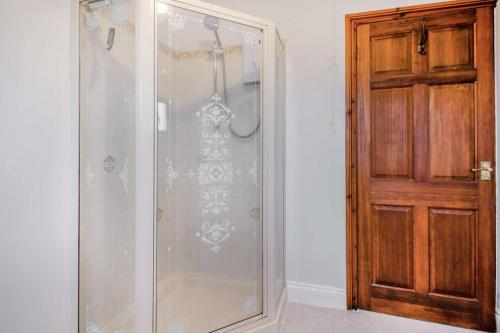 a shower with a glass door next to a wooden door at 4 Bed in Tenby oc-vv27177 in Manorbier