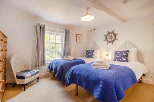 ein Schlafzimmer mit zwei Betten mit blauer Bettwäsche und einer Uhr an der Wand in der Unterkunft 3 Bed in Westleton Saxmundham oc-est in Westleton