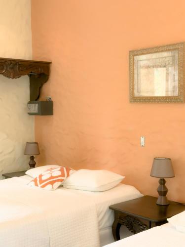 a bedroom with two beds and a table with two lamps at Hotel Condesa in Comayagua