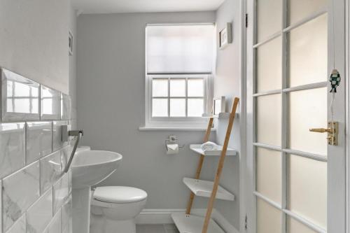 a white bathroom with a toilet and a window at 2 Bed in Southwold oc-eastgn in Southwold