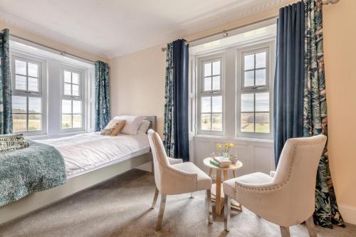 a bedroom with a bed and two chairs and windows at 5 Bed in Biddlestone oc-b30105 in Alnham