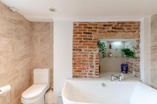 a bathroom with a white tub and a brick wall at 3 Bed in Wooler oc-m31820 in Wooler
