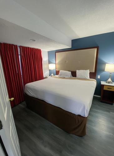 a bedroom with a large bed with red curtains at Extended Stay of Charleston in Charleston