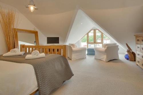 a bedroom with a bed and two white chairs at 2 Bed in Porthleven oc-4stelv in Porthleven