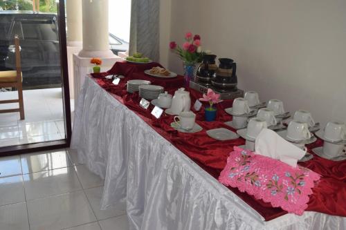a long table with cups and plates on it at Jambura Inn in Gorontalo