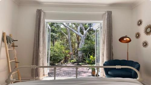 a bedroom with a bed and a large window at Forries Beach Cottage in Wamberal