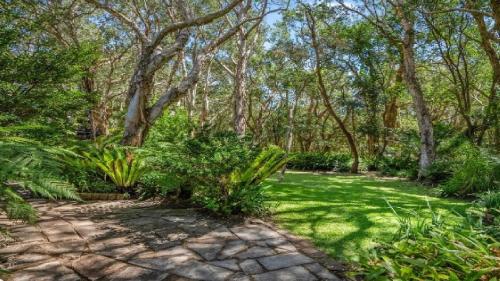 a garden with grass and trees and a path at Forries Beach Cottage in Wamberal